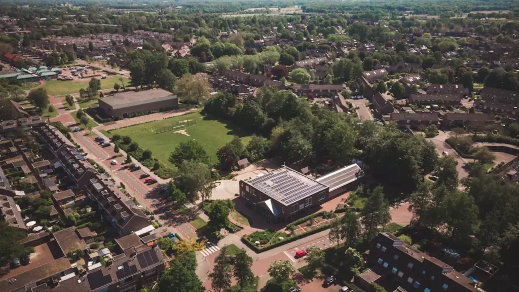 Vue aérienne d'une école primaire entourée d'espaces verts dans un quartier résidentiel.