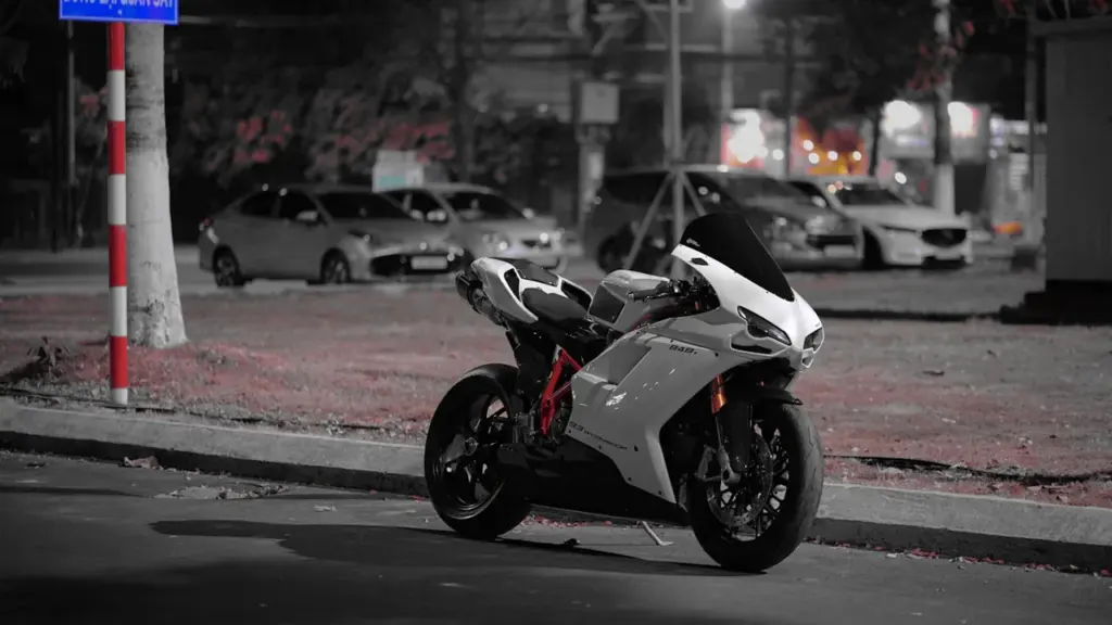 Une moto sportive blanche stationnée sur une rue urbaine le soir.