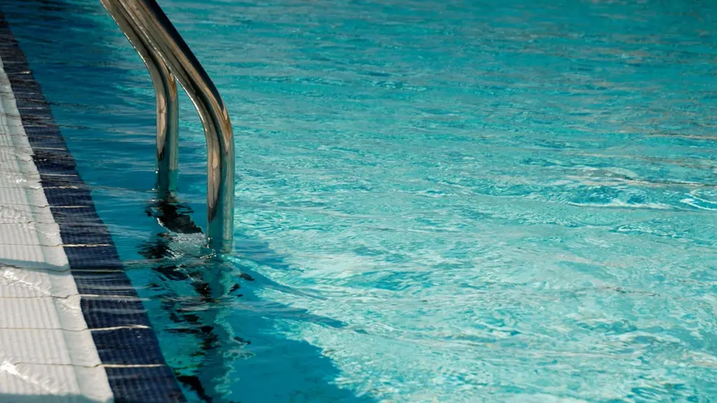 Gros plan sur une échelle métallique au bord d'une piscine publique.