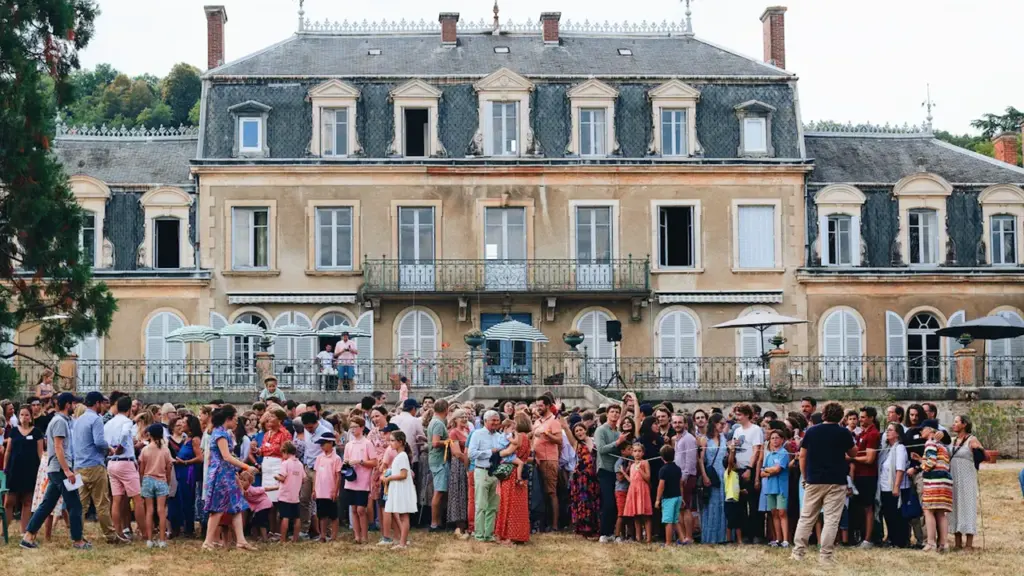 Un grand groupe de personnes réuni devant le majestueux palais historique à Dijon.