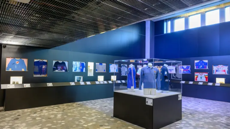 Exposition de maillots historiques de football français exposés dans des vitrines murales et centrales.