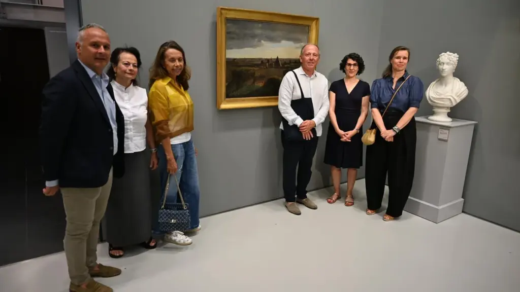 Un groupe de six personnes pose devant un tableau ancien dans une galerie d'art.