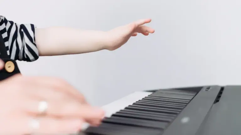 Gros plan sur les mains d'un enfant apprenant à jouer du piano au conservatoire.