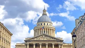 Le dôme du Panthéon à Paris avec un drapeau français sous un ciel nuageux.