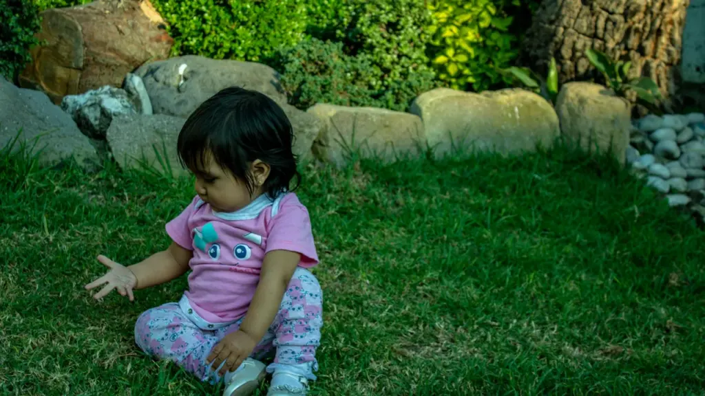 Une petite fille jouant tranquillement sur l'herbe dans un jardin botanique.