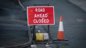 Panneau de signalisation indiquant une route fermée avec un cône de chantier orange.