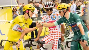 Trois cyclistes professionnels en tenue de course se serrent la main sur leurs vélos.