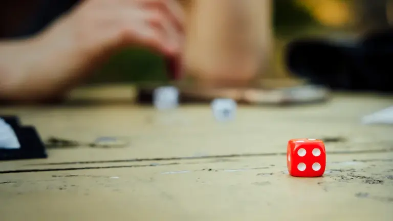 Gros plan sur un dé rouge posé sur une table en bois.