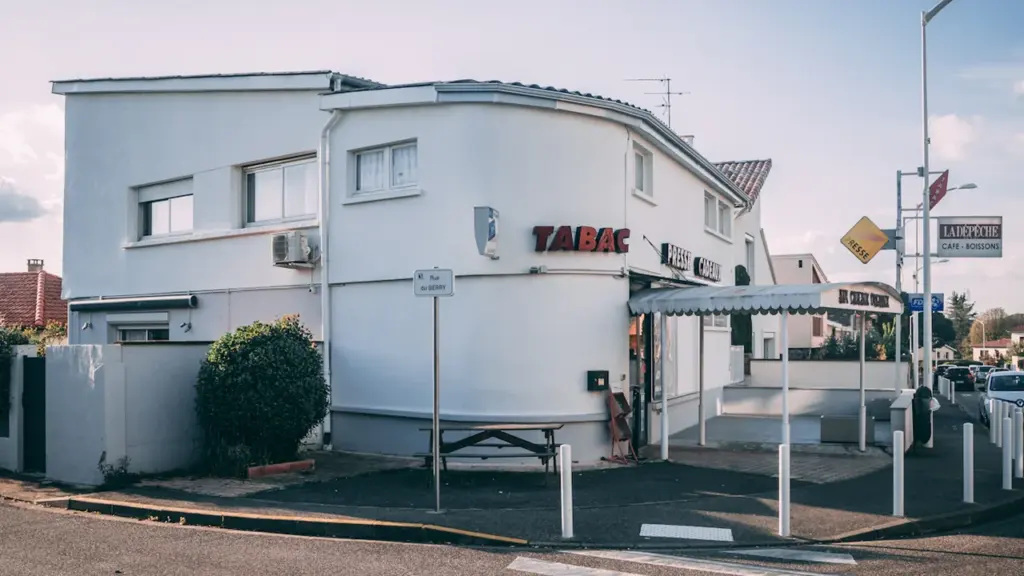 Façade d'un bâtiment blanc avec une enseigne Tabac dans une rue française.