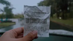 Une main tient un ticket avec un code-barres, illustrant le concept de verbalisation.
