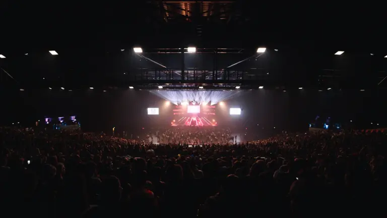 Une foule enthousiaste dans une salle de concert sombre avec des jeux de lumières.