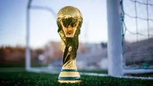 Le trophée doré de la Coupe du Monde de football devant un filet de but.