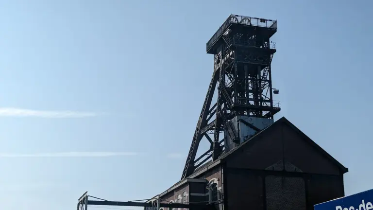 Ancienne tour d'extraction minière emblématique sous un ciel bleu dégagé à Saint-Étienne.