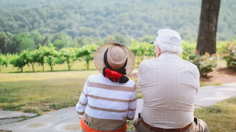 Un couple de seniors assis admirant un paysage verdoyant lors d'une sortie touristique.