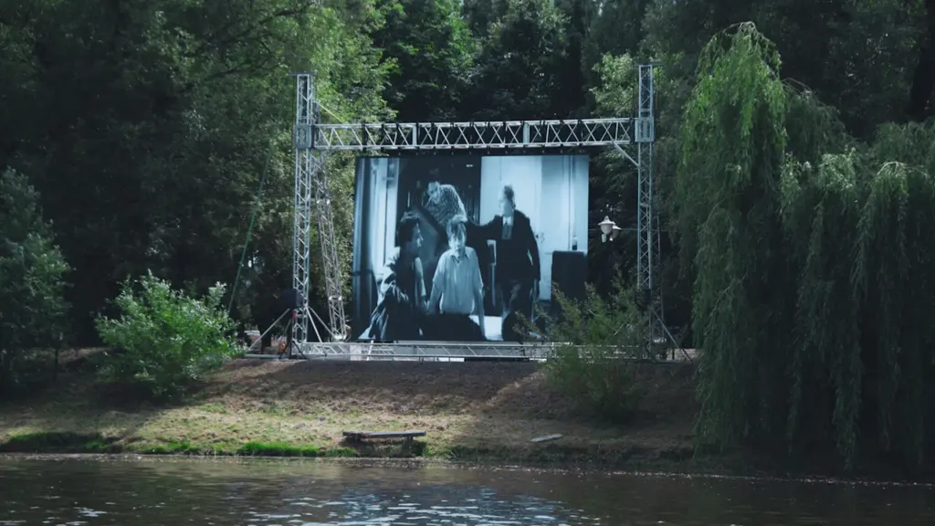 Grand écran de cinéma installé en plein air au bord d'une rivière.