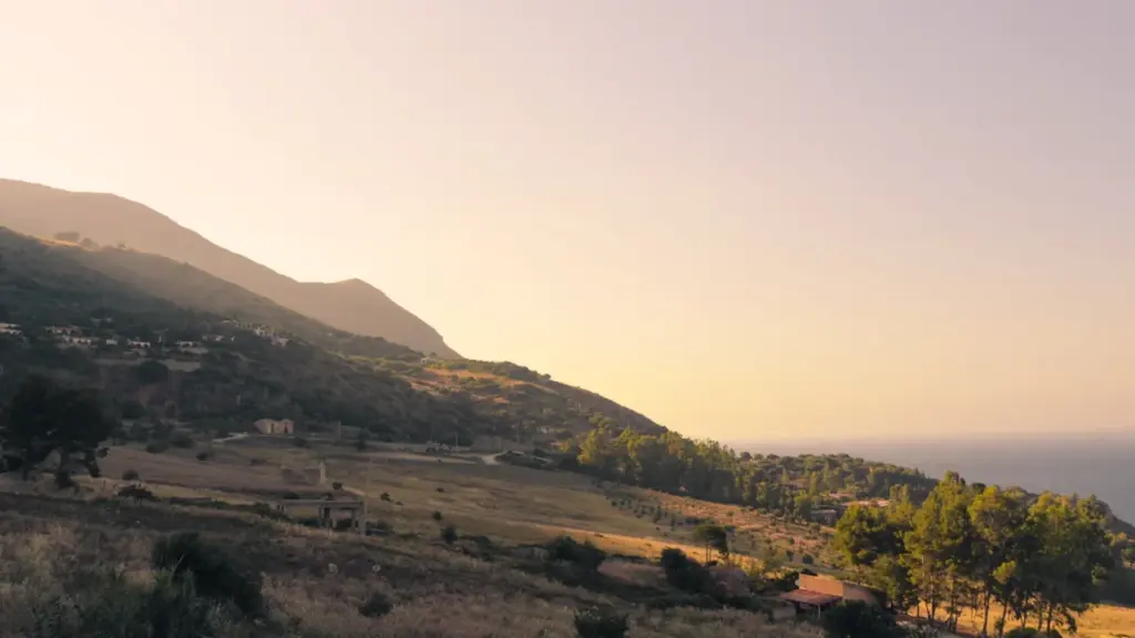 Paysage montagneux avec une végétation dense et sèche sous un soleil intense.