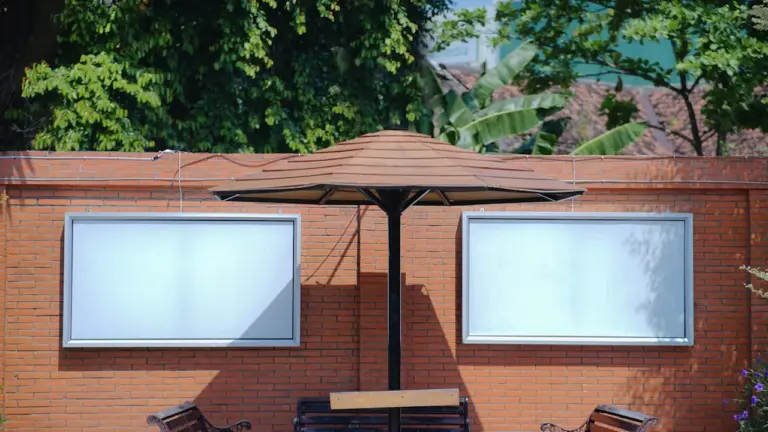 Panneau publicitaire extérieur vide sur un mur en briques avec des bancs publics.