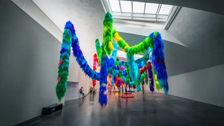 Une installation artistique colorée et moderne suspendue dans une galerie d'art contemporain lumineuse.