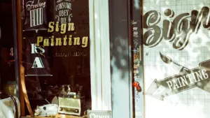 Vitrine d'un atelier de signalétique avec lettrages peints à la main sur le verre.