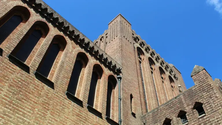 Façade en briques rouges d'un bâtiment historique avec des fenêtres cintrées élégantes.