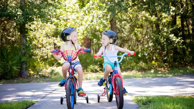 Deux jeunes enfants portant des casques font du vélo sur une piste cyclable.