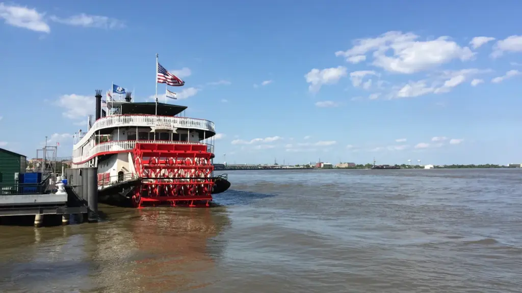 Un bateau à aubes traditionnel amarré le long d'une rive sous un ciel bleu.