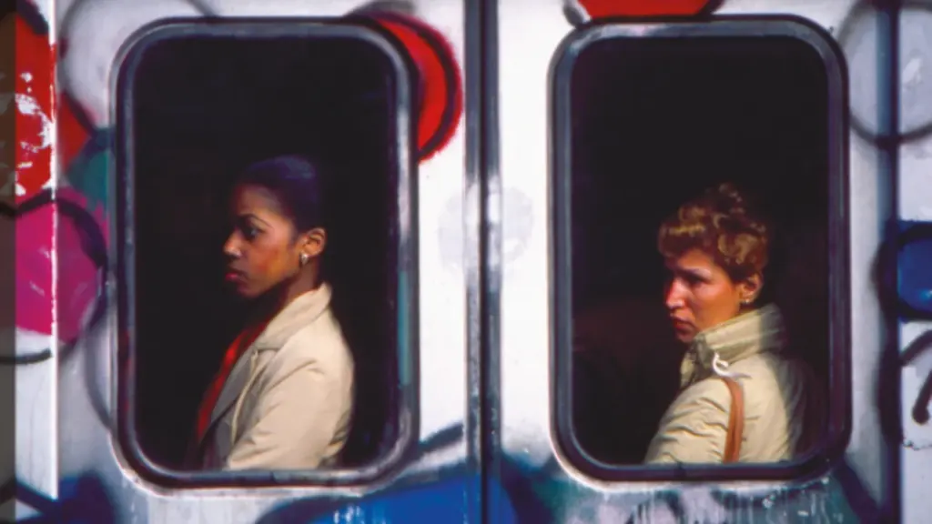 Deux femmes regardent par les fenêtres d'un train couvert de graffitis colorés.