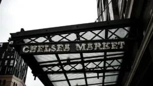 Une enseigne métallique suspendue au-dessus d'un marché urbain typique et animé.