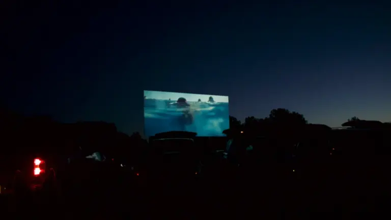 Un écran de cinéma en plein air projetant un film sous un ciel étoilé.