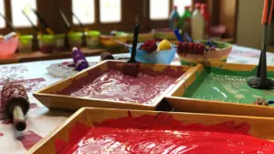 Plateaux en bois remplis de peinture colorée pour un atelier artistique pour enfants.