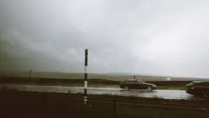 Voitures circulant sur une route sous un ciel d'orage menaçant et pluvieux.
