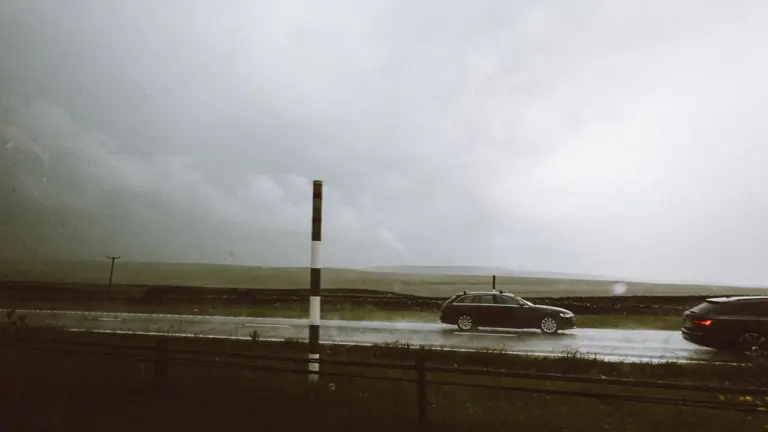 Voitures circulant sur une route sous un ciel d'orage menaçant et pluvieux.