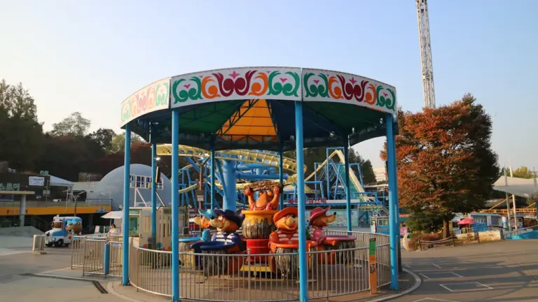 Un manège coloré pour enfants dans un parc d'attractions sous un ciel dégagé.
