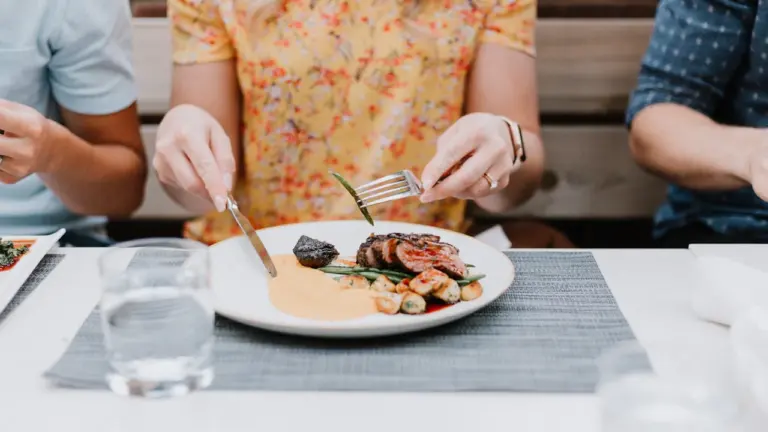 Des personnes partageant un repas convivial autour d'une table dressée avec soin.