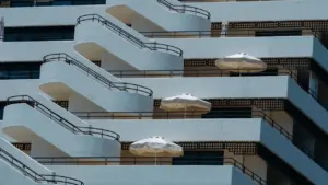 Architecture moderne avec balcons et parasols sur une façade d'immeuble ensoleillée.