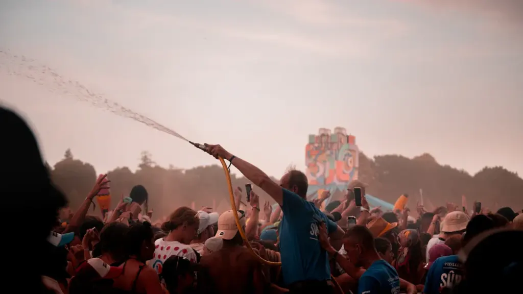 Foule lors d'un événement festif estival avec des jets d'eau rafraîchissants en plein air.