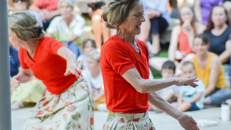 Deux femmes en tenue rouge interprétant une performance artistique lors d'un événement public.