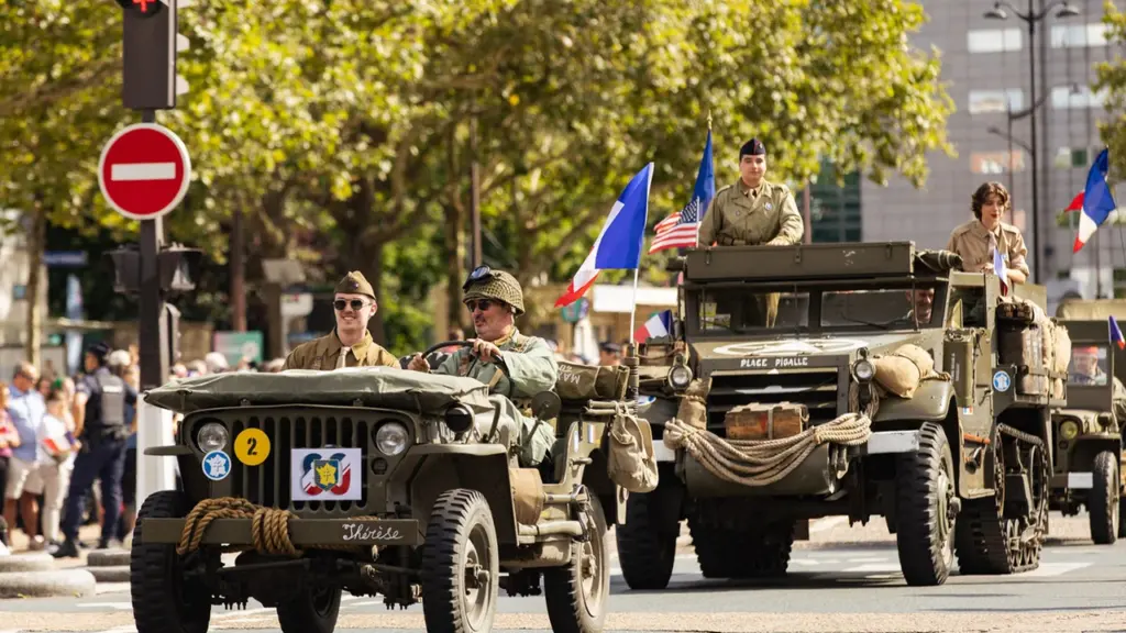 Des soldats en uniformes d'époque conduisent des jeeps militaires historiques lors d'un défilé commémoratif.