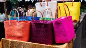 Sacs cabas colorés et tressés exposés sur un étal de marché local.