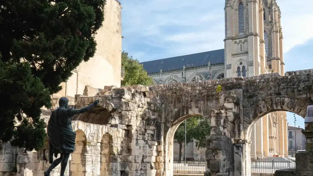 Une statue en bronze sur socle devant les ruines d'un mur historique et l'église.
