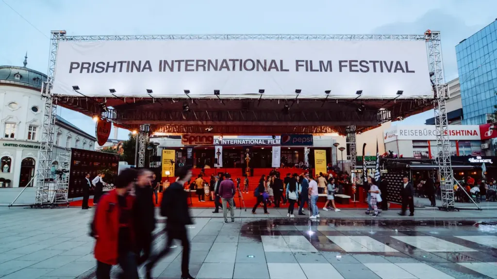 Une grande banderole de festival de cinéma installée sur une place publique animée.