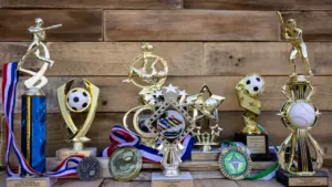Collection de trophées sportifs dorés posés sur une table en bois rustique